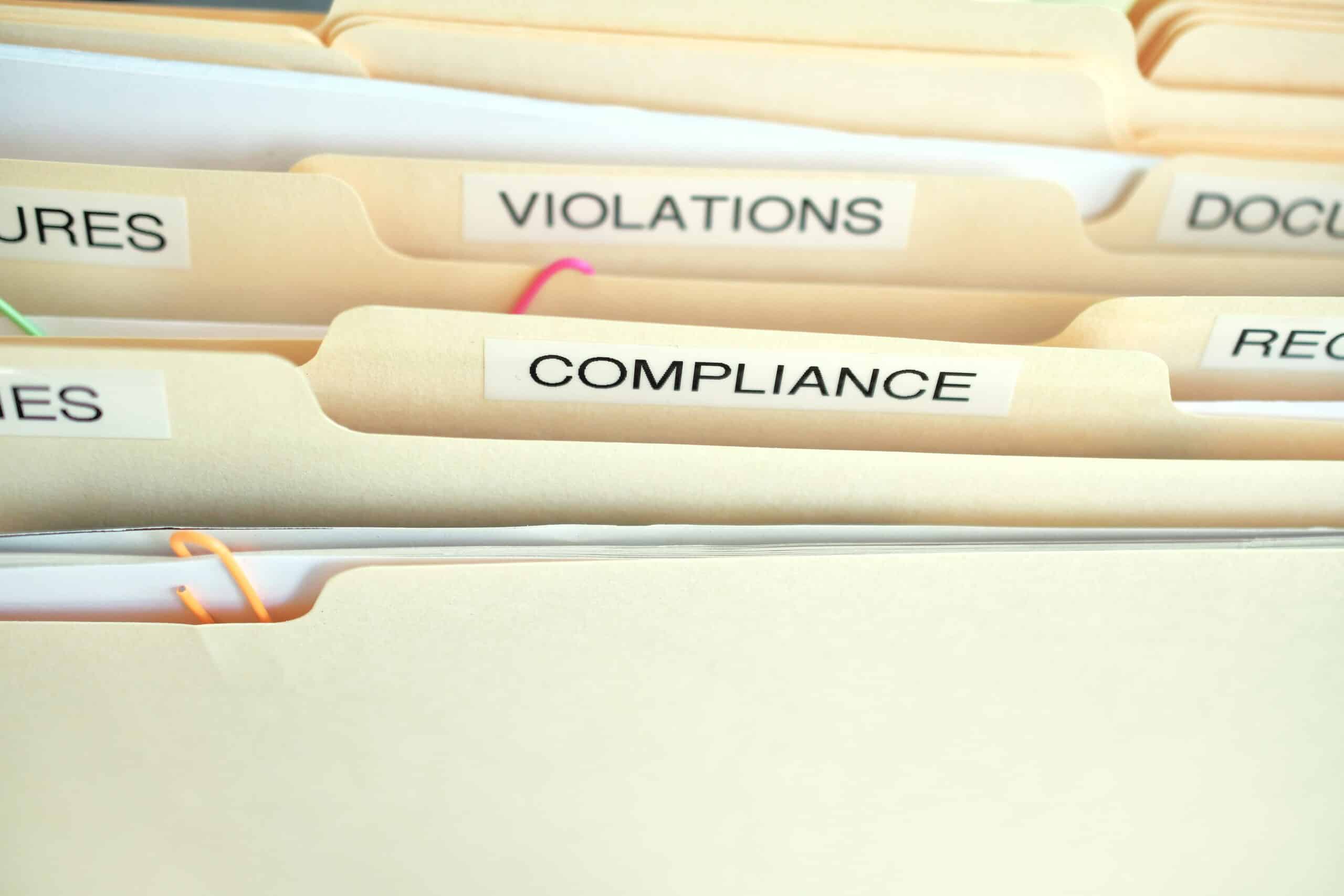 File folders titled compliance, and violations