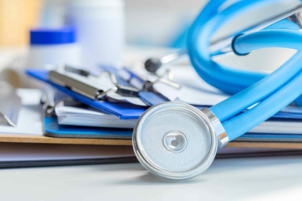 Stethoscope lying on medical forms and clipboards