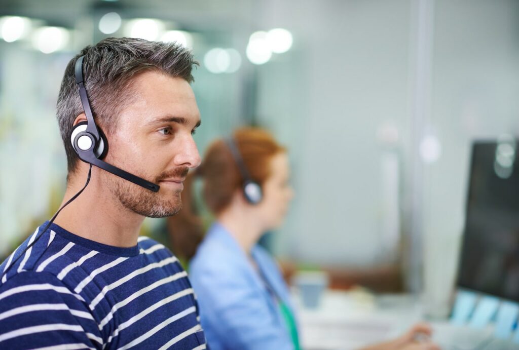 Co-managed IT support providers wearing headphones and looking into computer